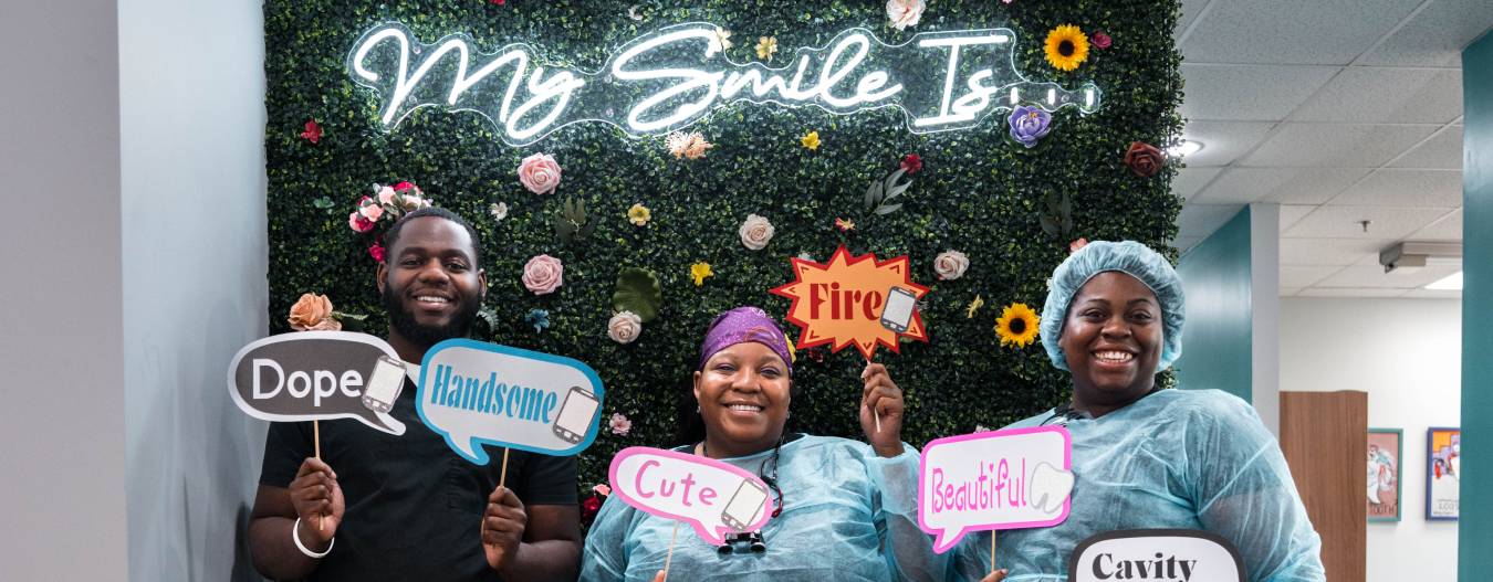 Team member holding up text signs in front of fun floral wall